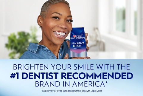 Woman smiling holding Crest 3DWhitestrips Sensitive Bright pack. Brighten Your Smile with the #1 Dentist Recommended Brand in America.