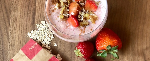 Instant Oatmeal packet spilling out next to strawberry smoothie on a table.