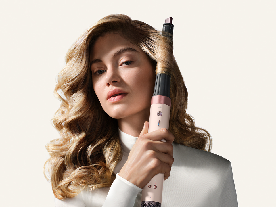 Model curls her hair with the Dyson Conical curling barrel.