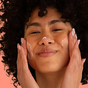 A young woman applying Balancing Repair Moisturizer to her face with her hands