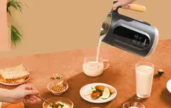 A table with a variety of foods and a beverage being poured out of the nut milk maker.