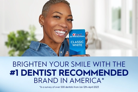 Woman smiling holding Crest 3DWhitestrips Classic White + Light pack. Brighten Your Smile with the #1 Dentist Recommended Brand in America.