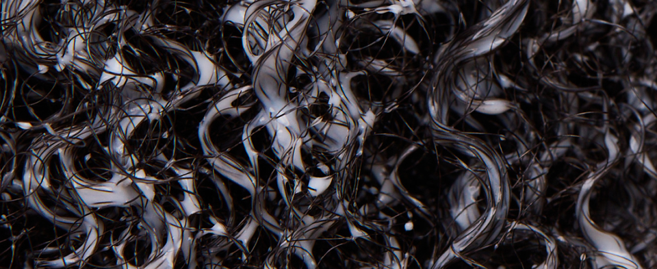 Close up shot of curly wet hair covered in conditioner, next to rinsing instructions