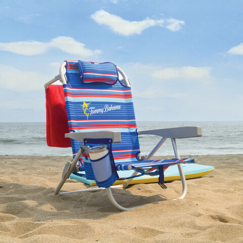 Beach chair on the beach with towel hanging from back of chair.