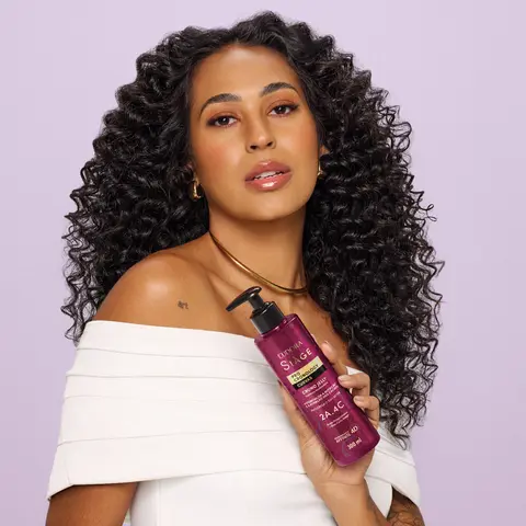 Imagem de uma mulher de cabelos cacheados e volumosos segurando o Finalizador Crono.Jelly Siàge Pro Cronology Curvas.