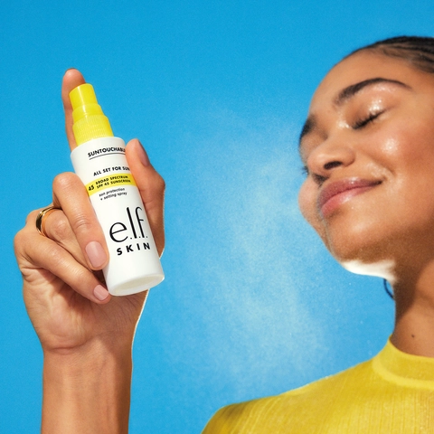 A model spraying e.l.f. SKIN&#39;s Suntouchable All Set For Sun SPF 45