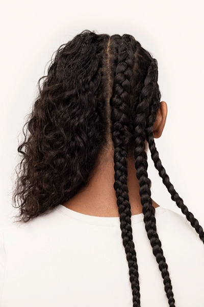 Woman seen from the back with half head in braids, half head hair out of braids.