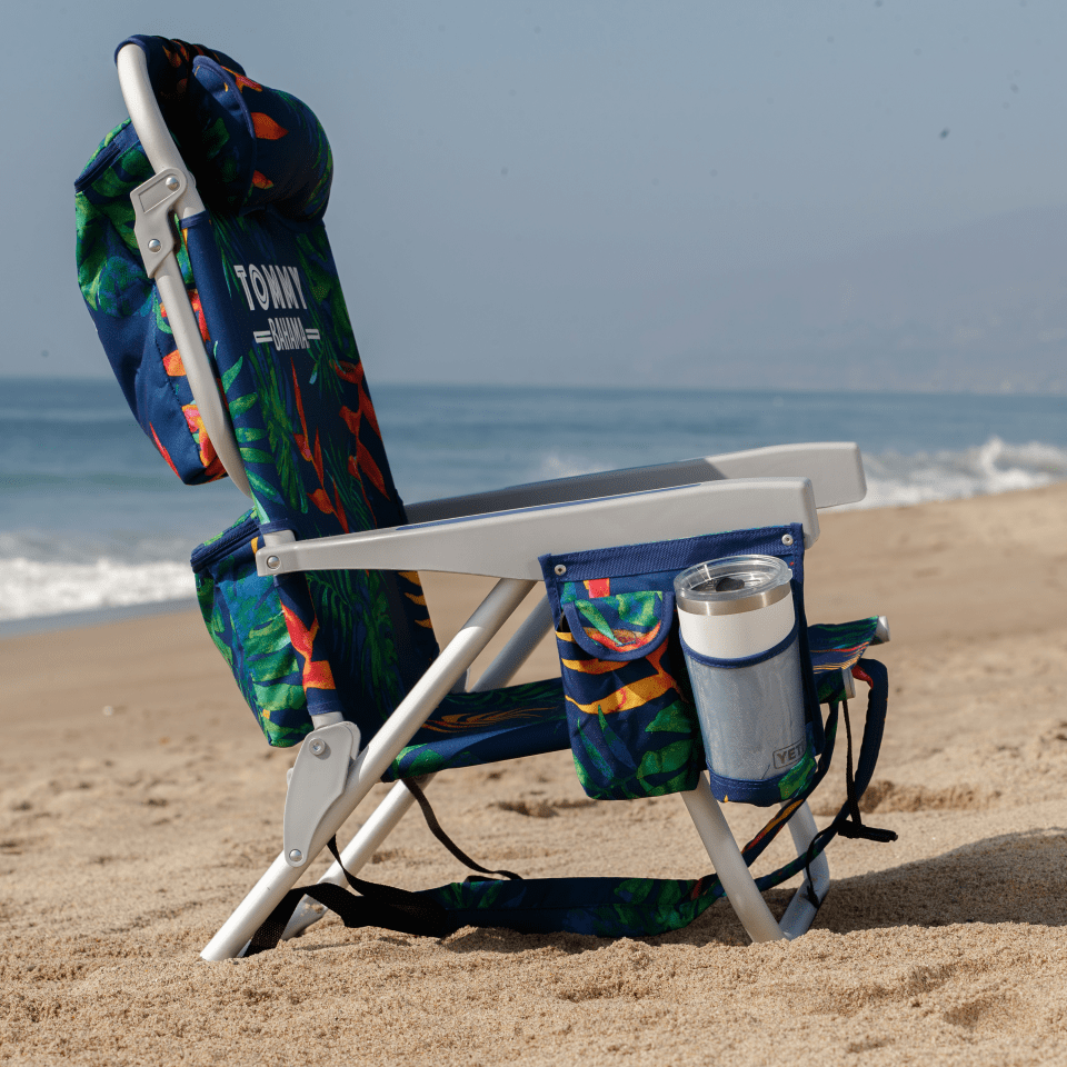 Profile of a beach chair on the beach with a cup in the cup holder. 
