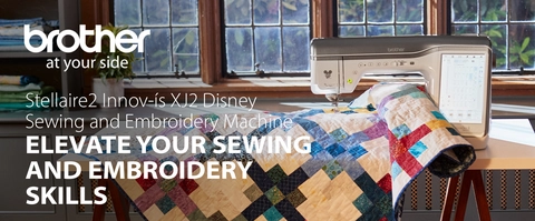 Headline:  Stellaire2 Innov-ís XJ2 Disney Sewing and Embroidery Machine Subhead: ELEVATE YOUR SEWING AND EMBROIDERY SKILLS; Image of machine in room setting with large quilt 