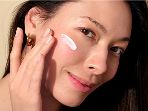 Woman applying Clear Face Serum Sunscreen to her cheek