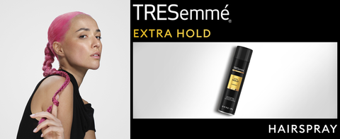 Woman with pink hair wearing a long braid next to Extra Hold Hairspray bottle and black accents.