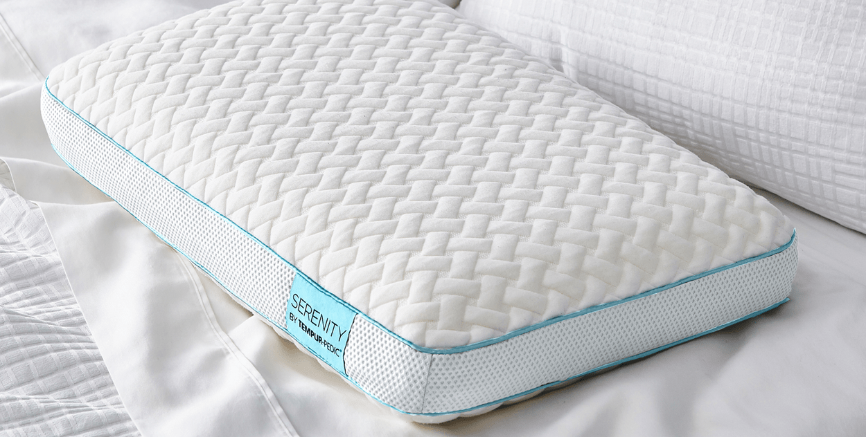 Image: Pillow with cover on lays at angle on bed, showing mesh side panels and blue Serenity label.