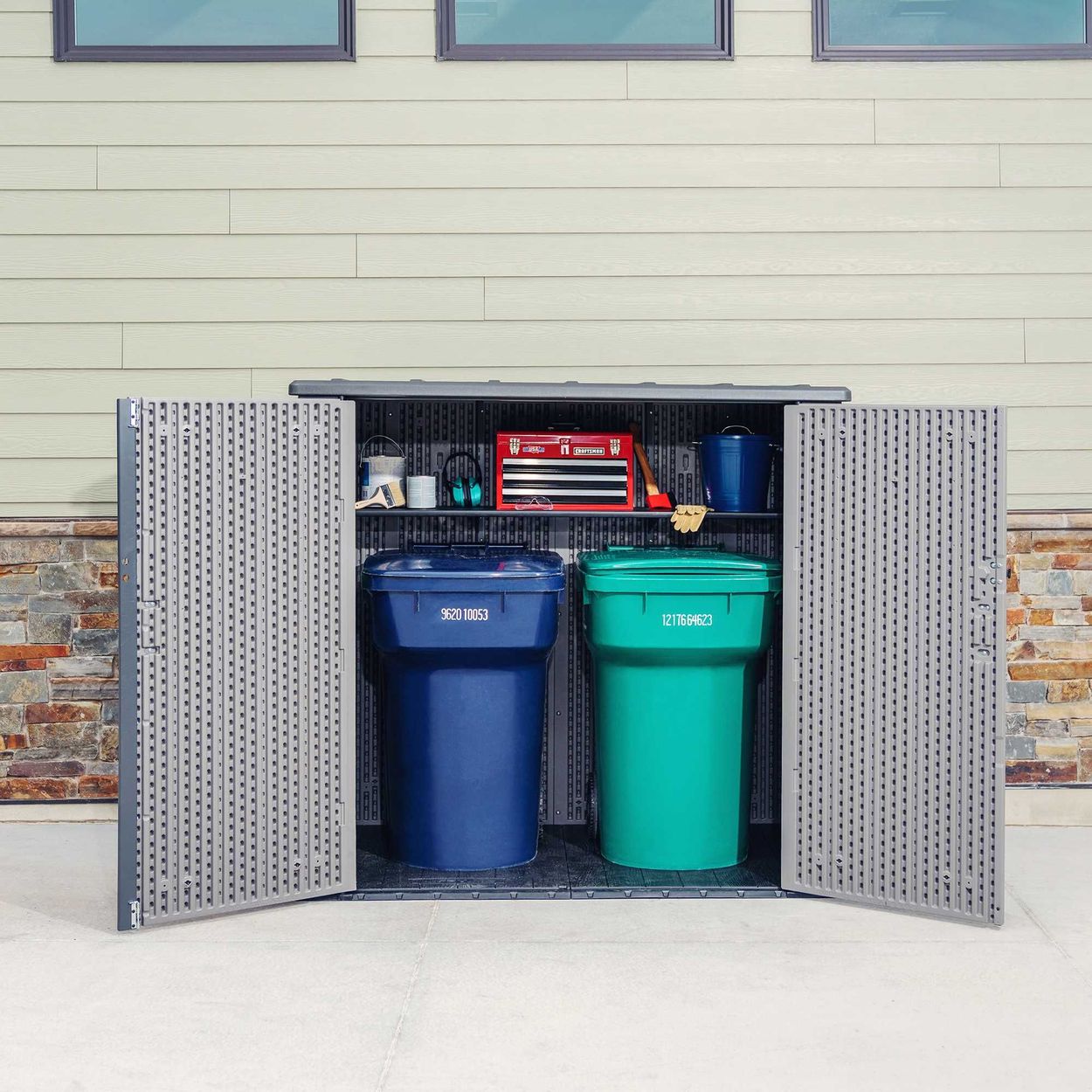 Open Utility Shed with two large garbage cans inside and several tools on the shelf inside of the shed.