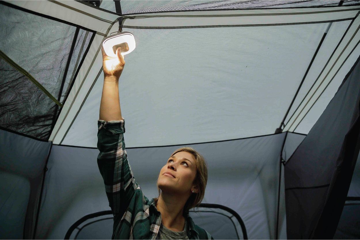 Woman placing light on ceiling of tent