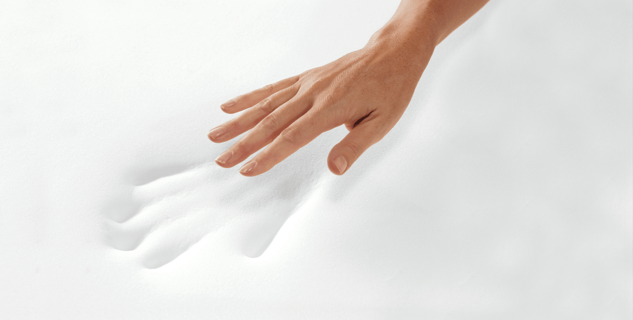 Image: hand hovers above handprint left on white adaptive memory foam.